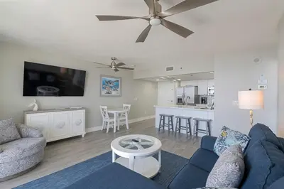 a living room with a blue couch and a ceiling fan at Long Beach Tower 3 #305 Beachfront Renovation in Panama City Beach