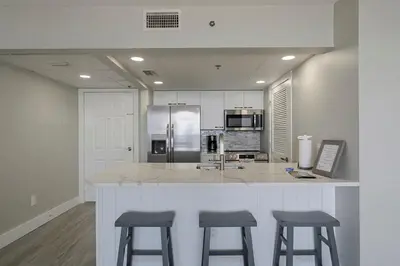 a kitchen with three bar stools and a counter top at Long Beach Tower 3 #305 Beachfront Renovation in Panama City Beach