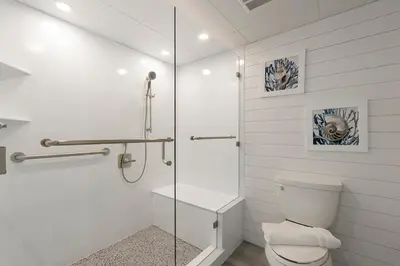 a bathroom with a toilet and a glass shower at Long Beach Tower 3 #305 Beachfront Renovation in Panama City Beach