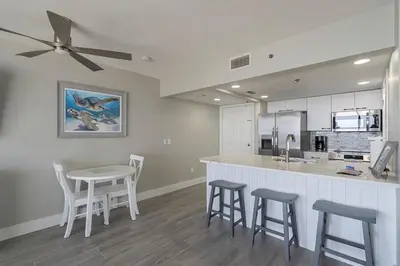 a kitchen with a bar with stools and a table at Long Beach Tower 3 #305 Beachfront Renovation in Panama City Beach
