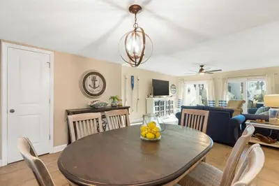 a dining room and living room with a table and chairs at Largo Mar 143 - Sand-Side Paradise Townhome in Panama City Beach