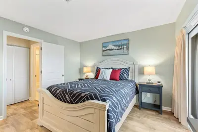 a bedroom with a bed with a blue and white comforter at Largo Mar 143 - Sand-Side Paradise Townhome in Panama City Beach