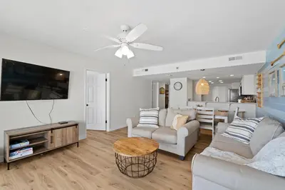 a living room with white furniture and a flat screen tv at Commodore 606 3 BR 3 BA Sleeps 12 in Panama City Beach