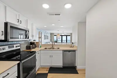 a kitchen with white cabinets and black appliances at Commodore 606 3 BR 3 BA Sleeps 12 in Panama City Beach