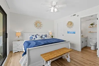 a white bedroom with a bed and a ceiling fan at Commodore 606 3 BR 3 BA Sleeps 12 in Panama City Beach