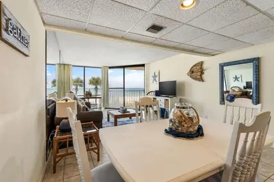 a dining room and living room with a table and chairs at Edgewater Windward 104 - 1 BR beachfront sleeps 4 in Panama City Beach