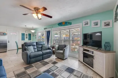 a living room with a television and a couch and chairs at 7131 Sunset Ave - Cottage by The Sea with pool in Panama City Beach