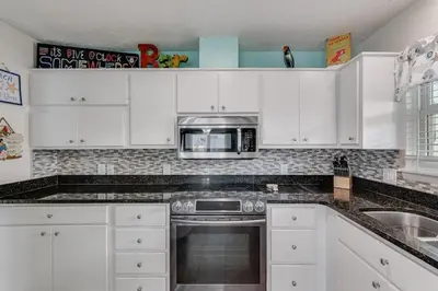 a kitchen with white cabinets and a microwave at 7131 Sunset Ave - Cottage by The Sea with pool in Panama City Beach