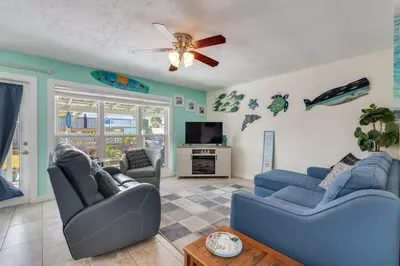 a living room with two blue couches and a tv at 7131 Sunset Ave - Cottage by The Sea with pool in Panama City Beach