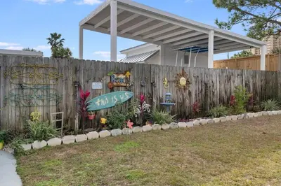 a wooden fence with a surfboard in a garden at 7131 Sunset Ave - Cottage by The Sea with pool in Panama City Beach