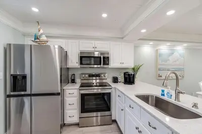 a kitchen with white cabinets and a stainless steel refrigerator at Edgewater T1 #709 - Sleeps 6 Amazing gulf views! in Panama City Beach