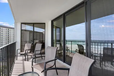 a balcony with chairs and tables and windows at Edgewater T1 #709 - Sleeps 6 Amazing gulf views! in Panama City Beach