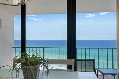 a room with a view of the ocean from a balcony at Edgewater T2 #911 Sleeps 10 with amazing sunsets! in Panama City Beach