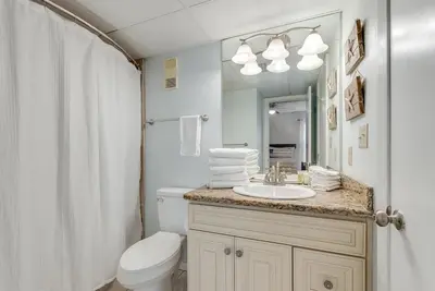 a bathroom with a toilet and a sink and a mirror at Edgewater T2 #911 Sleeps 10 with amazing sunsets! in Panama City Beach
