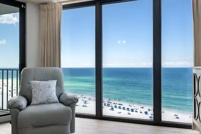 a chair in a room with a view of the ocean at Edgewater T2 #911 Sleeps 10 with amazing sunsets! in Panama City Beach