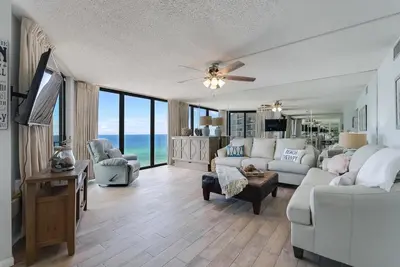 a living room with a white couch and a tv at Edgewater T2 #911 Sleeps 10 with amazing sunsets! in Panama City Beach