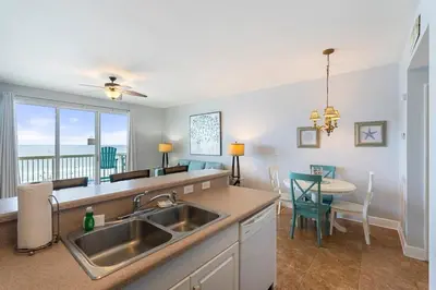 a kitchen with a sink and a dining room with a table at Celadon 307 1 BR 2 BA Oceanfront condo in Panama City Beach