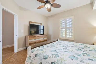 a bedroom with a bed and a flat screen tv at Celadon 307 1 BR 2 BA Oceanfront condo in Panama City Beach