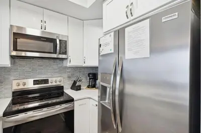 a kitchen with white cabinets and a stainless steel refrigerator at Celadon 1506 Beachfront 1 BR 2 BA sleeps 6 in Panama City Beach