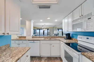 a kitchen with white cabinets and blue walls at Commodore 605 3 BR 3 BA with 2 Beachfront Masters in Panama City Beach