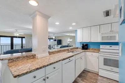 a kitchen with white cabinets and a view of the ocean at Commodore 605 3 BR 3 BA with 2 Beachfront Masters in Panama City Beach