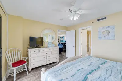 a bedroom with a bed and a tv and a mirror at Commodore 605 3 BR 3 BA with 2 Beachfront Masters in Panama City Beach