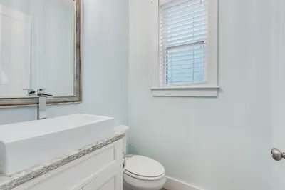 a white bathroom with a toilet and a mirror at Coastal Sands - 219 Sands Street in Panama City Beach