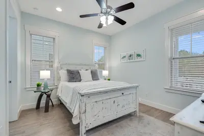 a white bedroom with a bed and a ceiling fan at Coastal Sands - 219 Sands Street in Panama City Beach