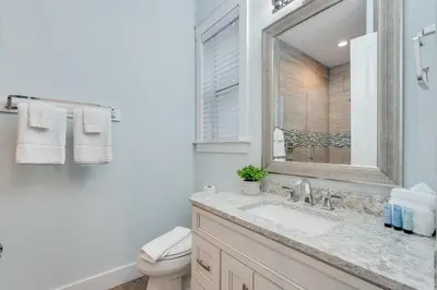 a bathroom with a sink and a toilet and a mirror at Coastal Sands - 219 Sands Street in Panama City Beach