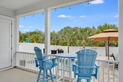 a patio with blue chairs and a table and an umbrella at Coastal Sands - 219 Sands Street in Panama City Beach