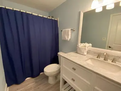 a bathroom with a toilet and a blue shower curtain at Celadon 207 beachfront 1 BR 2 BA Sleeps 6 in Panama City Beach