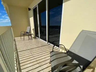 a balcony with a table and chairs on a house at Celadon 207 beachfront 1 BR 2 BA Sleeps 6 in Panama City Beach
