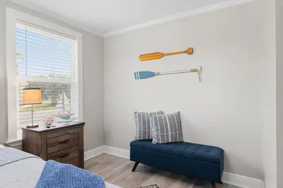 a bedroom with a blue chair and a baseball bat on the wall at 13900 Millcole Ave - Beachy Bungalow - Sleeps 10 in Panama City Beach