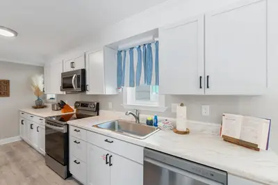 a kitchen with white cabinets and a sink at 13900 Millcole Ave - Beachy Bungalow - Sleeps 10 in Panama City Beach