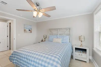 a bedroom with a bed and a ceiling fan at 13900 Millcole Ave - Beachy Bungalow - Sleeps 10 in Panama City Beach