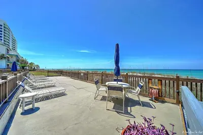 a patio with chairs and a table and umbrellas on the beach at Mariner East #201 1 BR 2 BA Amazing Balcony! in Panama City Beach