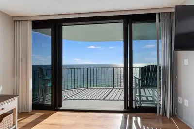 a living room with sliding glass doors with a view of the ocean at Watercrest 1603 - 2 BR 2 BA Beachfront Balcony in Panama City Beach