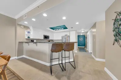 a kitchen with two bar stools at a counter at Boardwalk 2101 in Panama City Beach
