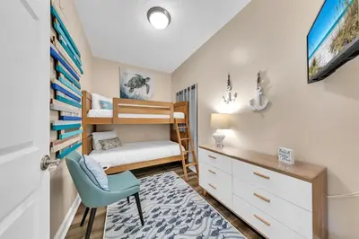 a bedroom with a bunk bed and a desk and a chair at Boardwalk 2101 in Panama City Beach