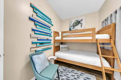 a room with two bunk beds and a chair at Boardwalk 2101 in Panama City Beach