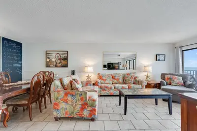 a living room with couches and a table and a chalkboard at 5th Floor Oceanview Getaway - Moondrifter in Panama City Beach