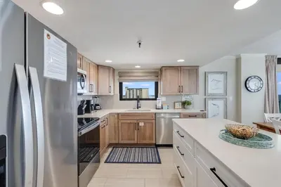 a kitchen with wooden cabinets and a stainless steel refrigerator at Watercrest 901 2 BR 2 BA sleeps 8 Amazing balcony! in Panama City Beach