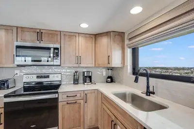 a kitchen with wooden cabinets and a sink and a window at Watercrest 901 2 BR 2 BA sleeps 8 Amazing balcony! in Panama City Beach