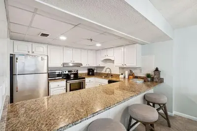 a kitchen with white cabinets and a stainless steel refrigerator at Watercrest 502 - Perfect Family Getaway 2BR 2 BA in Panama City Beach