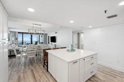 a white kitchen with a dining room and a dining table at Watercrest 902 - Ocean Pearl Retreat - Renovated! in Panama City Beach