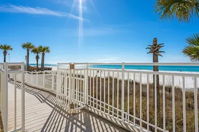 a white fence on the beach with palm trees at Watercrest 902 - Ocean Pearl Retreat - Renovated! in Panama City Beach
