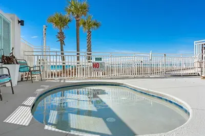 a swimming pool with palm trees and a fence at Watercrest 902 - Ocean Pearl Retreat - Renovated! in Panama City Beach