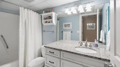 a bathroom with a sink and a toilet and a mirror at Watercrest 904 Beachfront 9th floor 3 BR 3 BA unit in Panama City Beach
