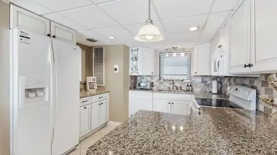 a kitchen with white cabinets and a granite counter top at Watercrest 904 Beachfront 9th floor 3 BR 3 BA unit in Panama City Beach
