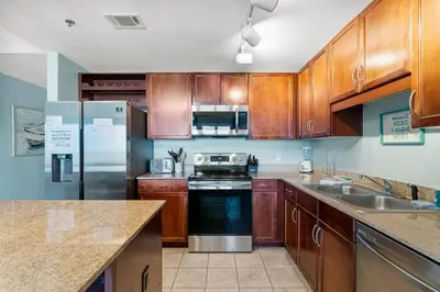 a kitchen with wooden cabinets and stainless steel appliances at Family-Friendly Laketown Wharf Retreat Near Pineapple Willy’s & Beach in Panama City Beach